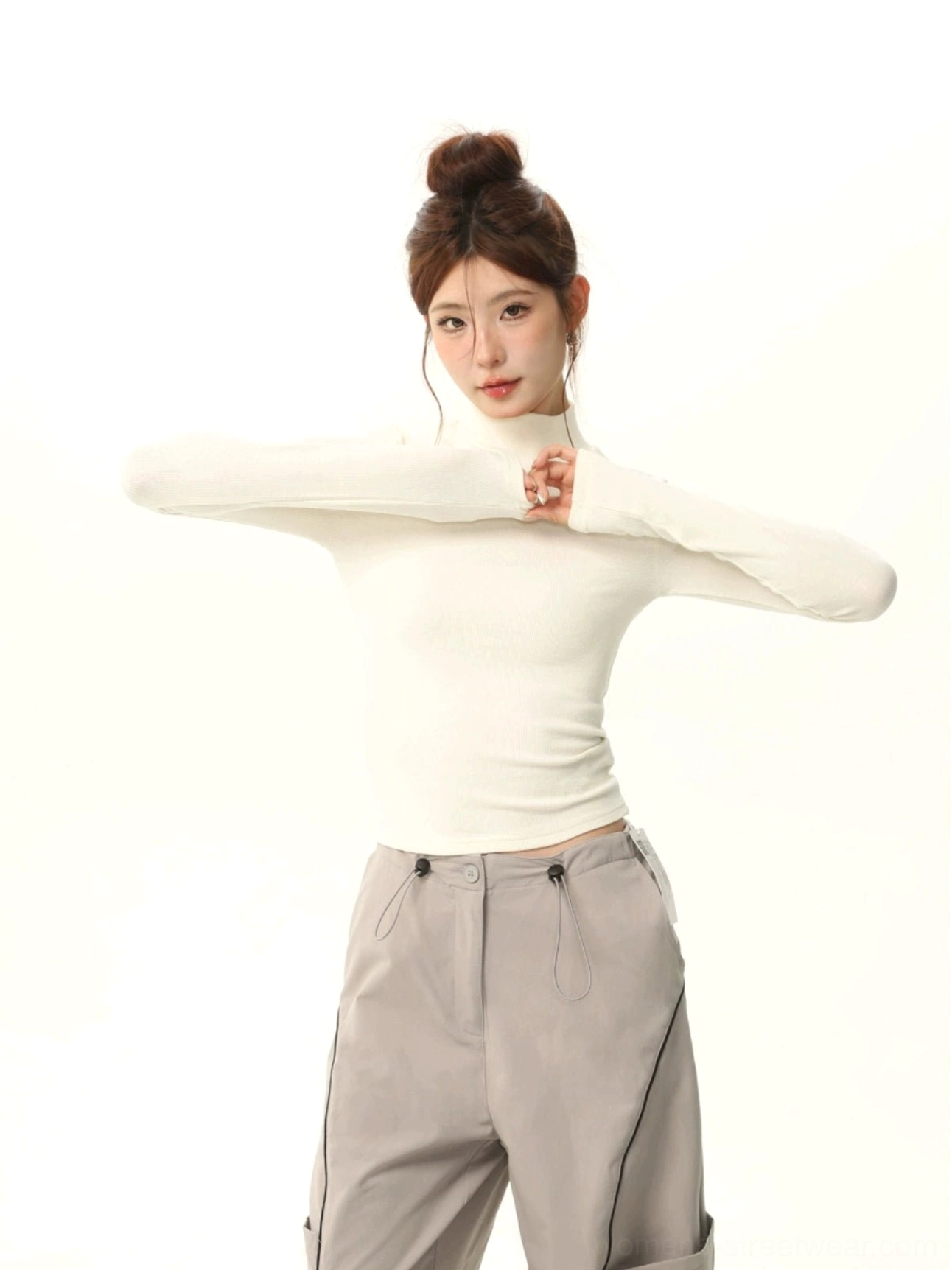Off-white brushed mock neck slim fit long sleeve streetwear top styled with grey wide-leg cargo pants on a female model