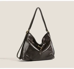 Dark brown buckle detail hobo shoulder bag shown from a front three-quarter angle with smooth PU leather-look finish, gold-tone hardware, decorative straps, and relaxed slouchy streetwear silhouette