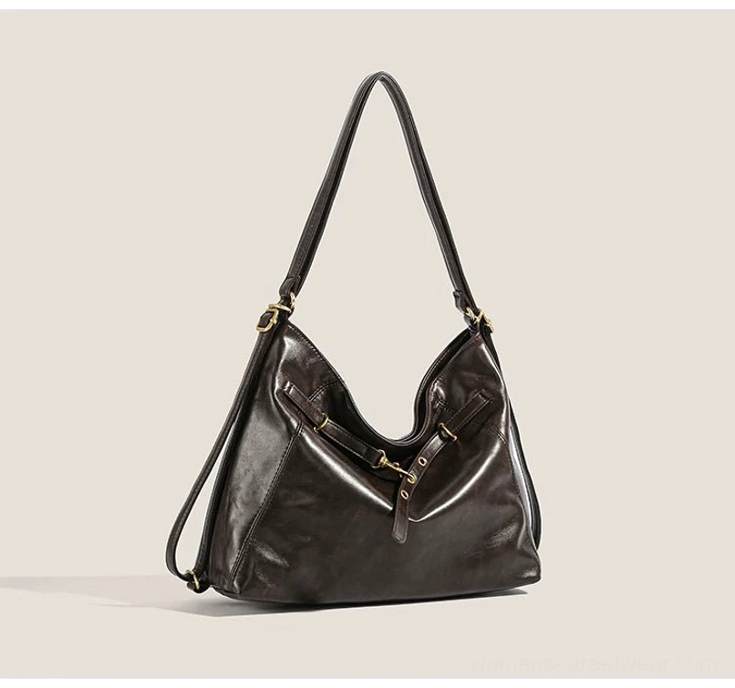 Dark brown buckle detail hobo shoulder bag shown from a front three-quarter angle with smooth PU leather-look finish, gold-tone hardware, decorative straps, and relaxed slouchy streetwear silhouette