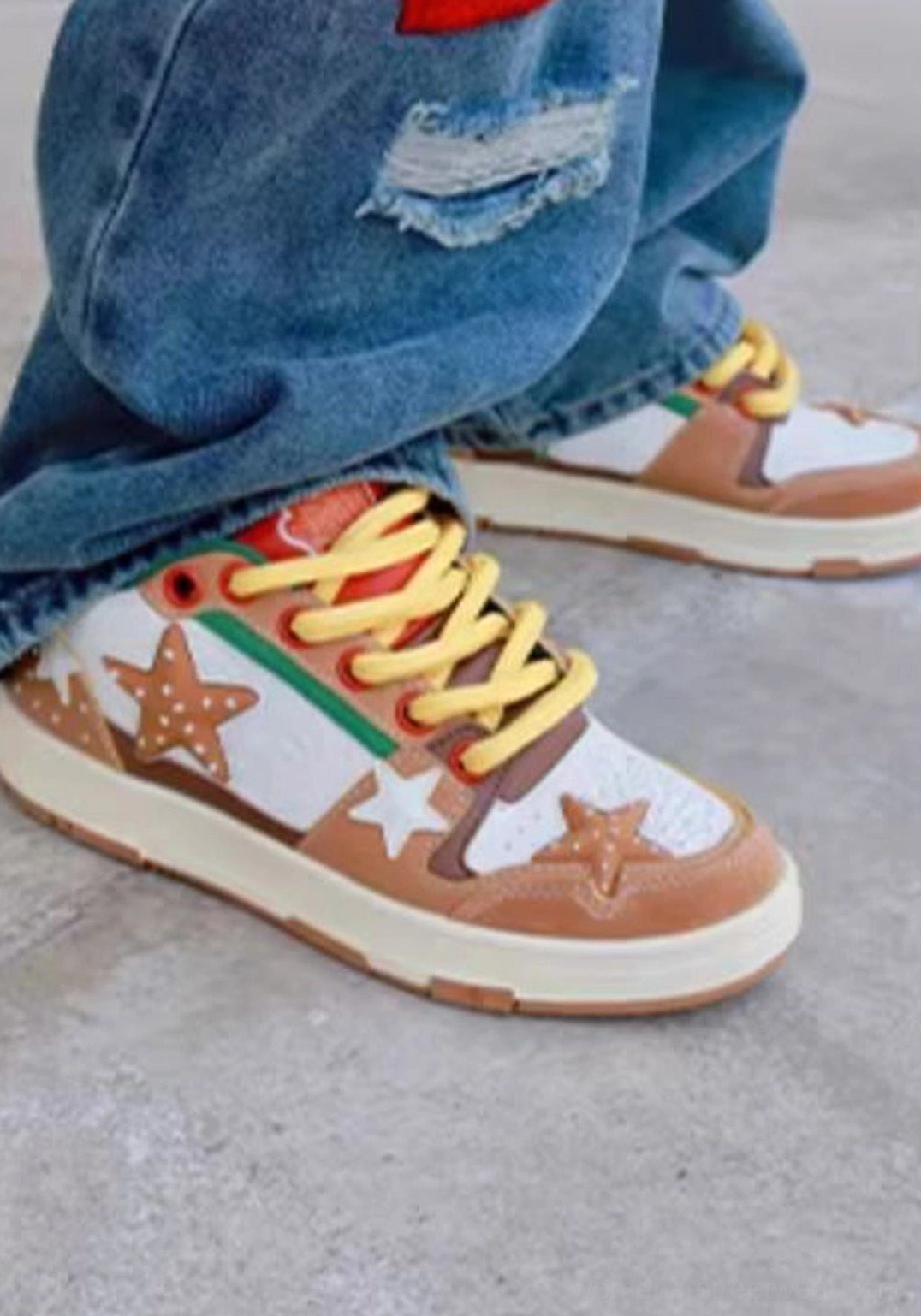 Side close-up of Burger Star low-top skate sneakers worn with jeans featuring oversized star patches brown white green panels and yellow laces