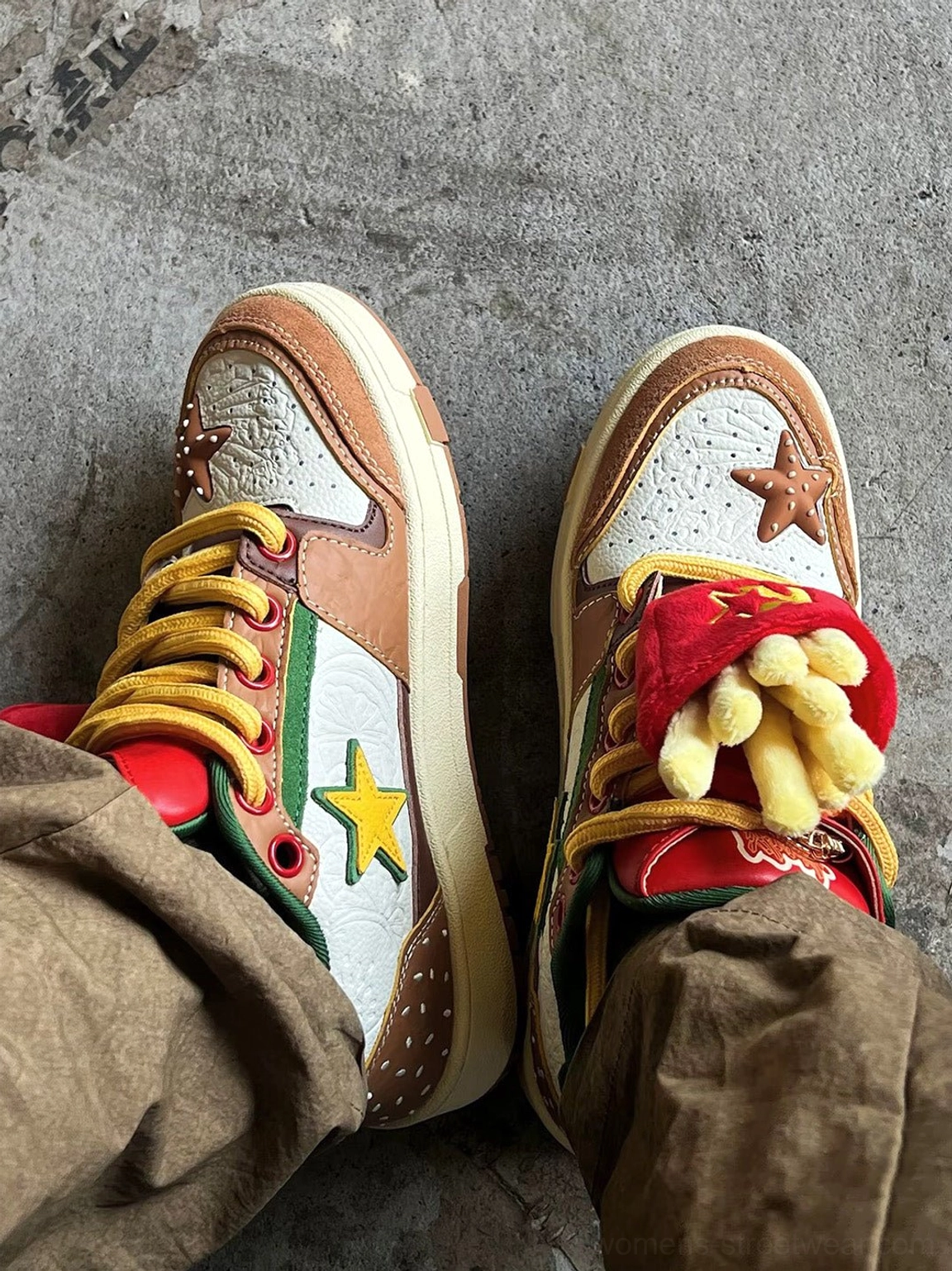 Top view of Burger Star low-top skate sneakers worn with brown cargo pants showing yellow laces and fries-inspired tongue charm