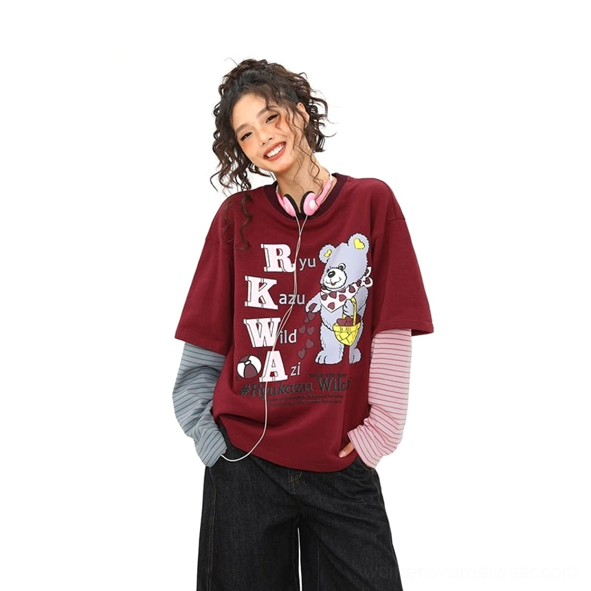 Low-angle front view of a burgundy bear graphic layered tee with pink and grey sleeves, pink headphones, and Y2K streetwear styling