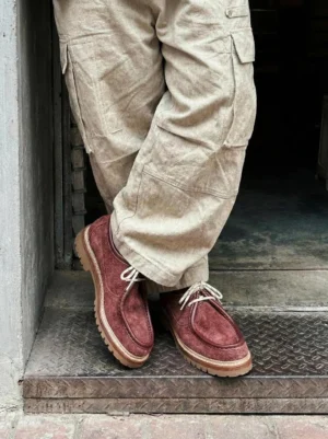 Model wearing burgundy moc-toe suede work loafers with beige cargo pants standing on metal step casual daily streetwear styling