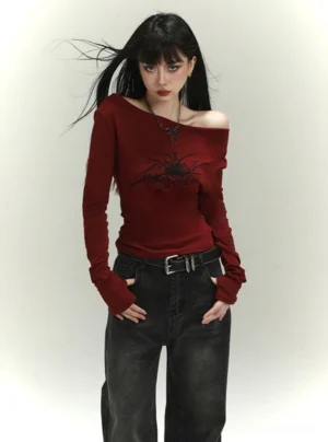 Burgundy off-shoulder spider graphic long-sleeve streetwear top styled with dark wide-leg jeans