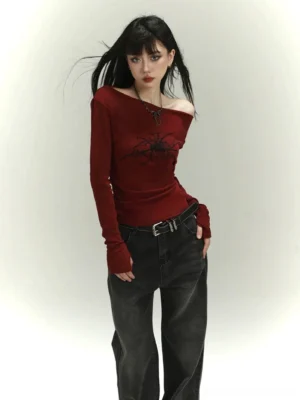 Side view of fitted burgundy off-shoulder spider print top with dark wide-leg denim