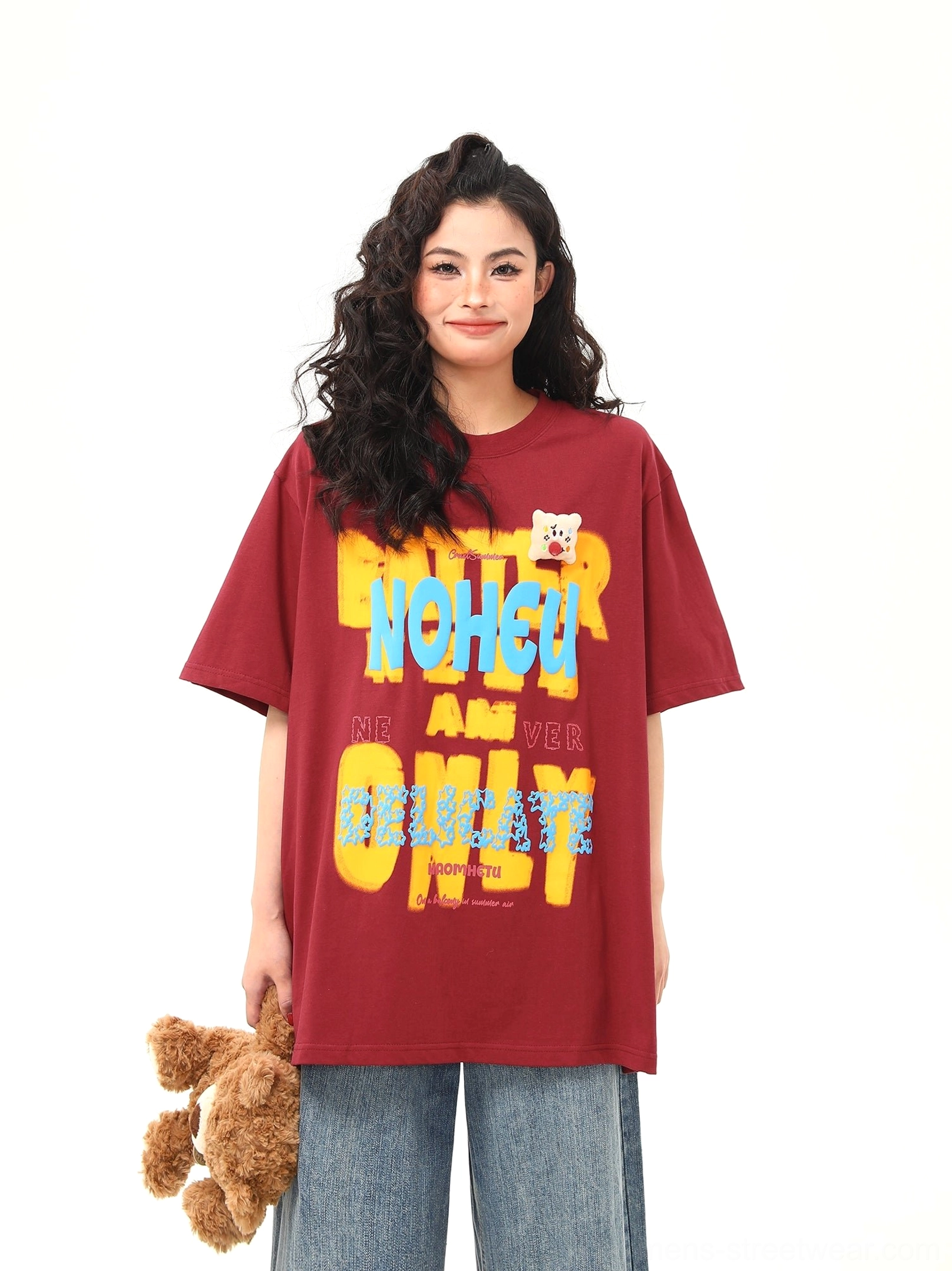 Front view of burgundy oversized graphic T-shirt with colorful retro print, crew neck, and teddy bear patch detail