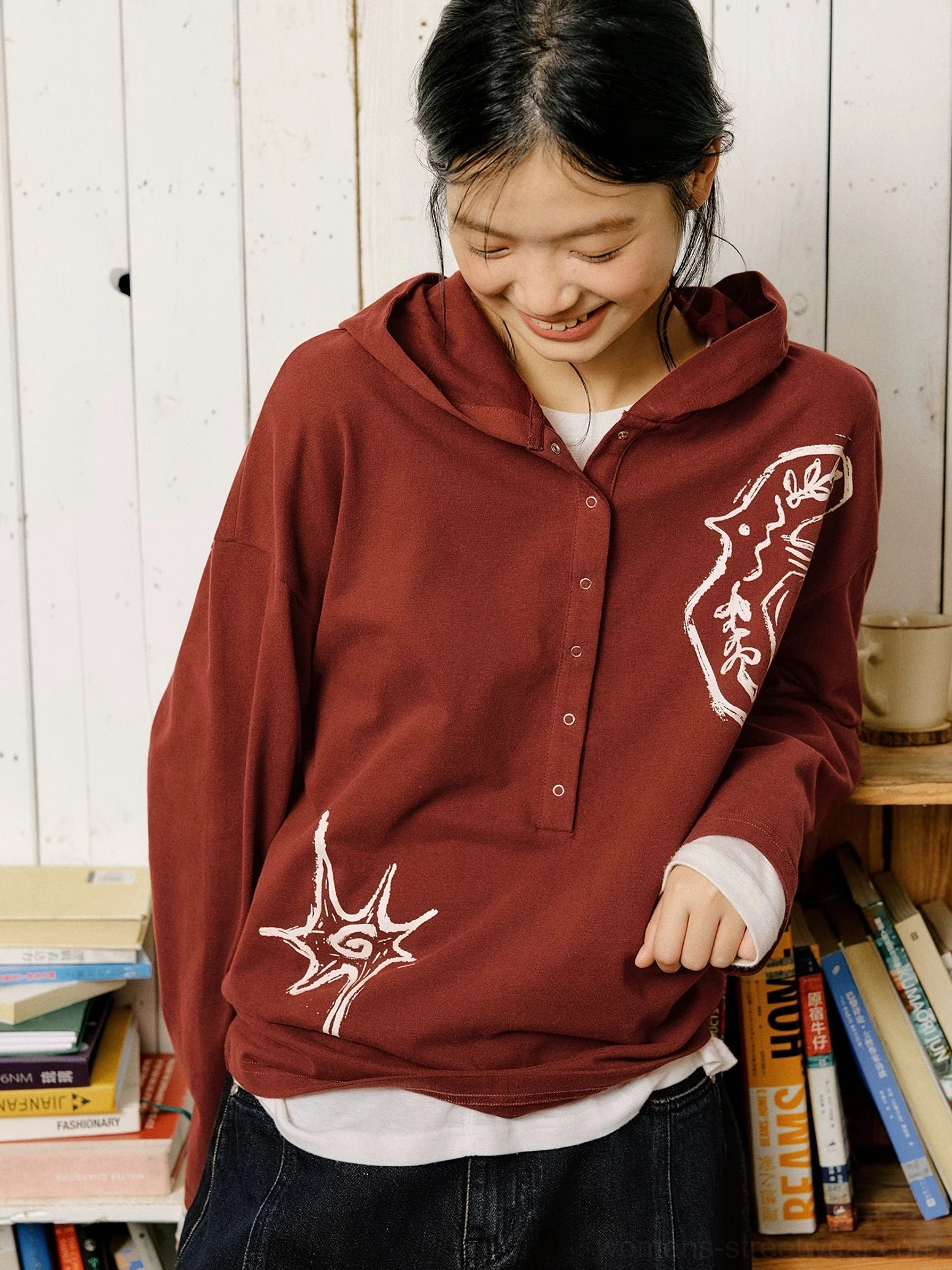 Burgundy red oversized embroidered Henley polo shirt layered over a white crew neck shirt with artistic graphic embroidery