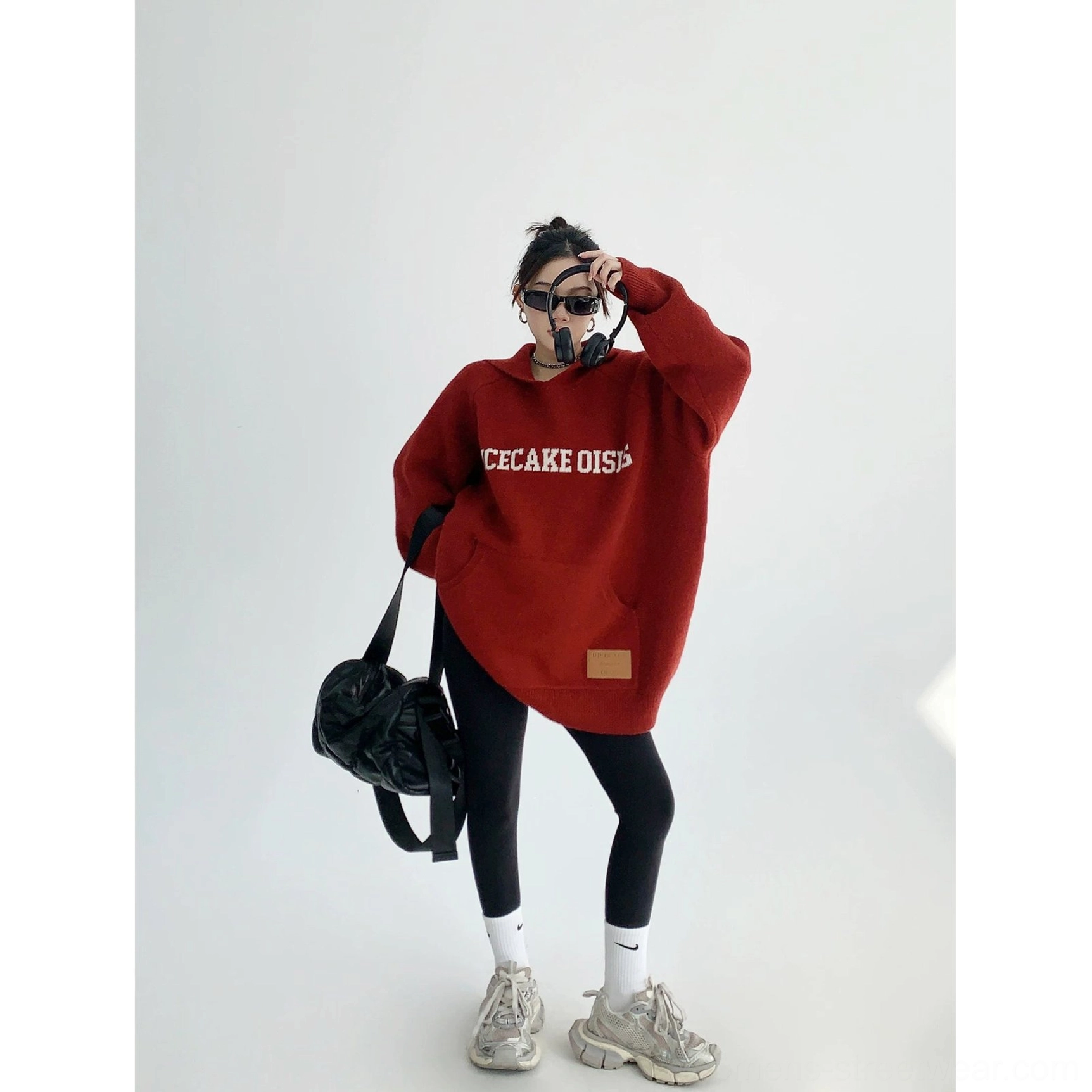 Burgundy red oversized knit hoodie with playful graphic lettering, thick warm texture, faux-leather hem patch, and relaxed proportions