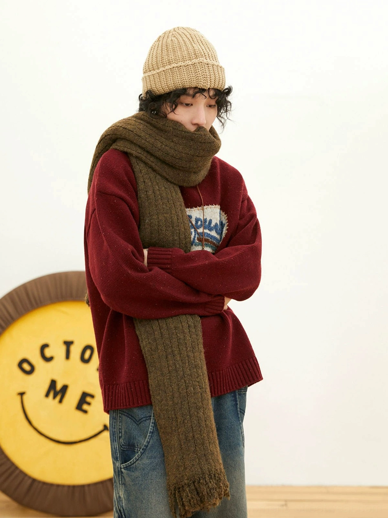 Burgundy relaxed fit vintage knit sweater with detailed front embroidered patch, long scarf, beanie, and washed blue wide-leg denim