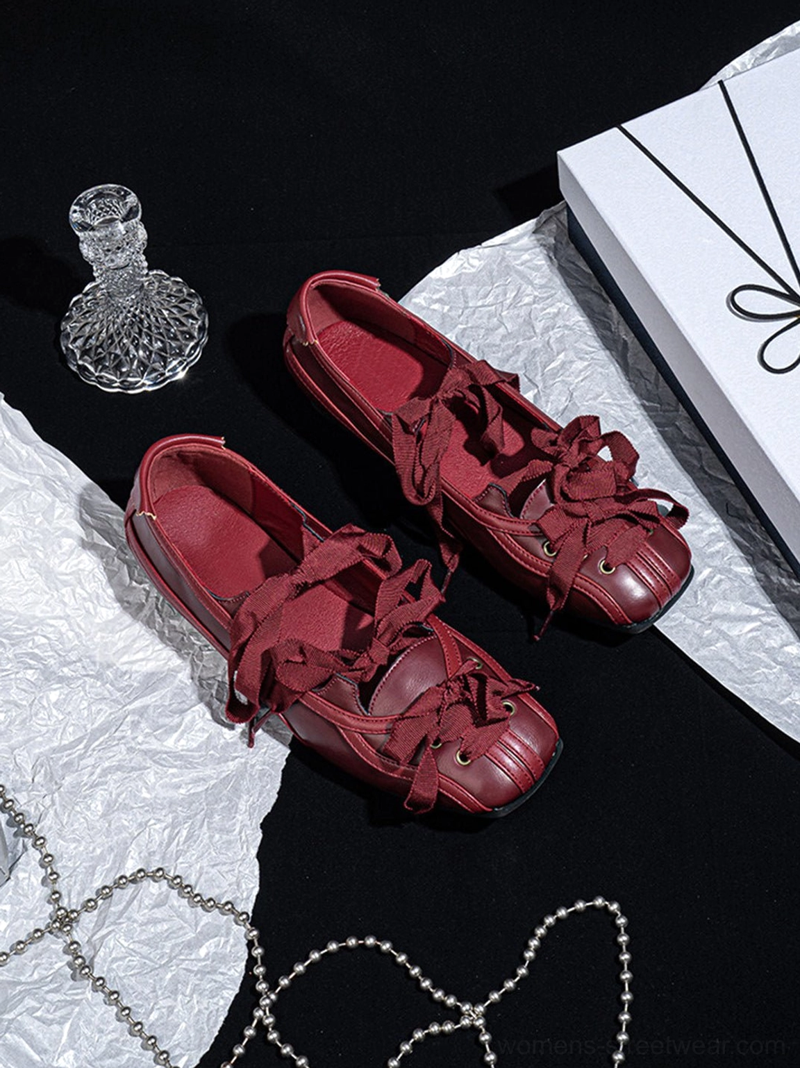 Burgundy ribbon lace-up ballet flats featuring decorative bows, metal eyelets, and a flat sole