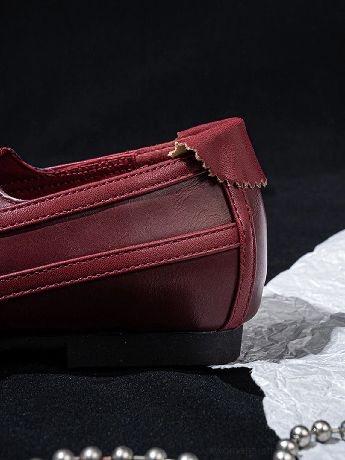Side close-up of burgundy ribbon lace-up ballet flats showing flat sole, stitching, and heel trim