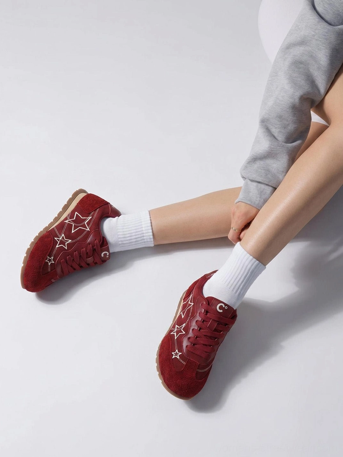 Side view of burgundy star embroidered low-top streetwear sneaker worn with white crew socks