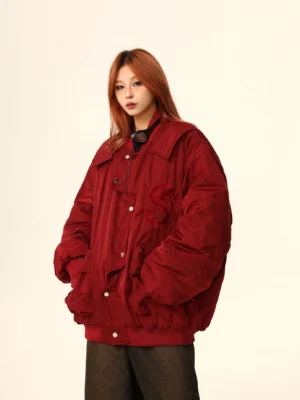 Burgundy varsity bomber jacket three quarter front view showing hidden snap placket, tonal chest embroidery, oversized fit, and side pockets