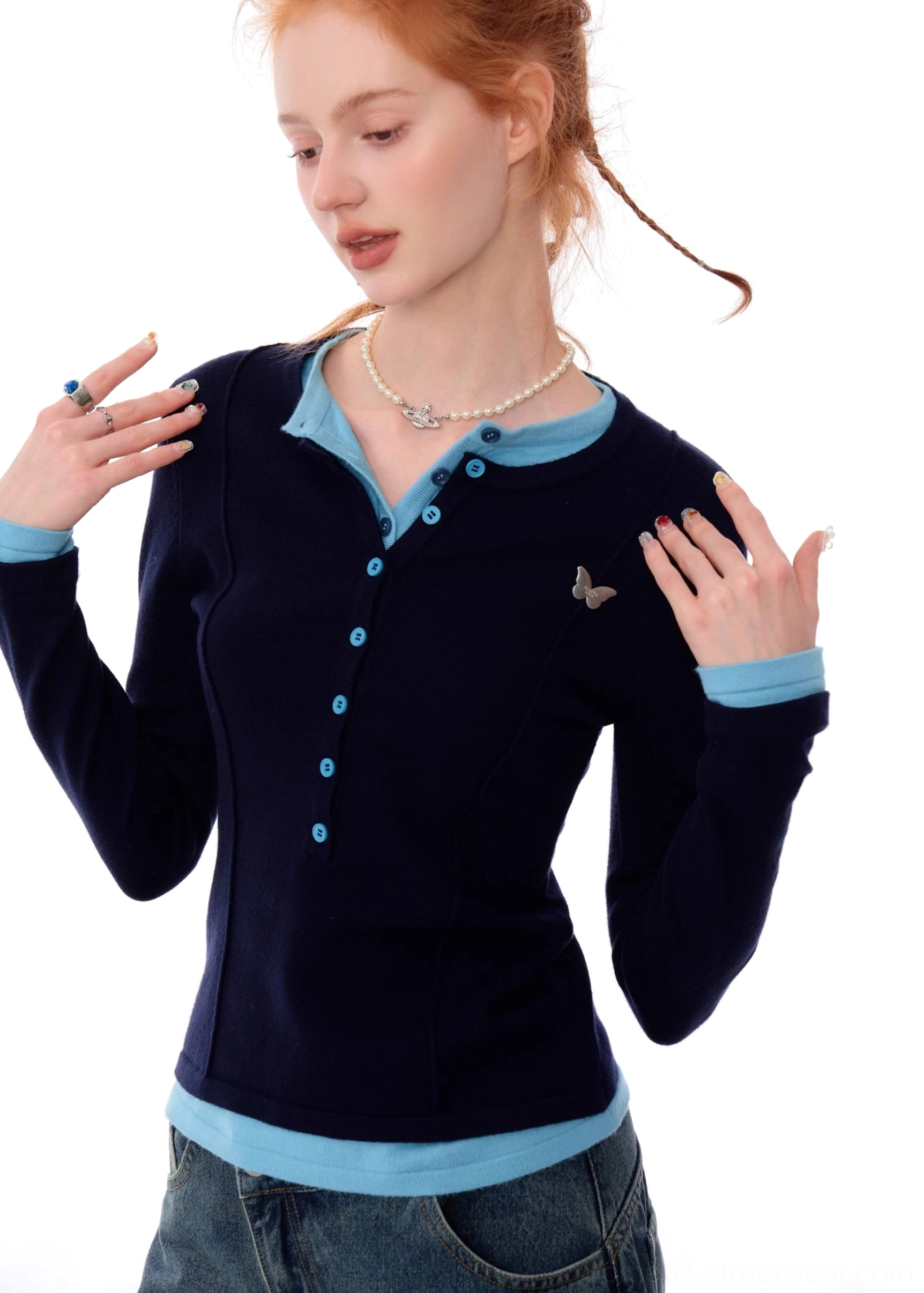 Detailed close-up of butterfly chest decoration and button Henley neckline on navy contrast trim knit top