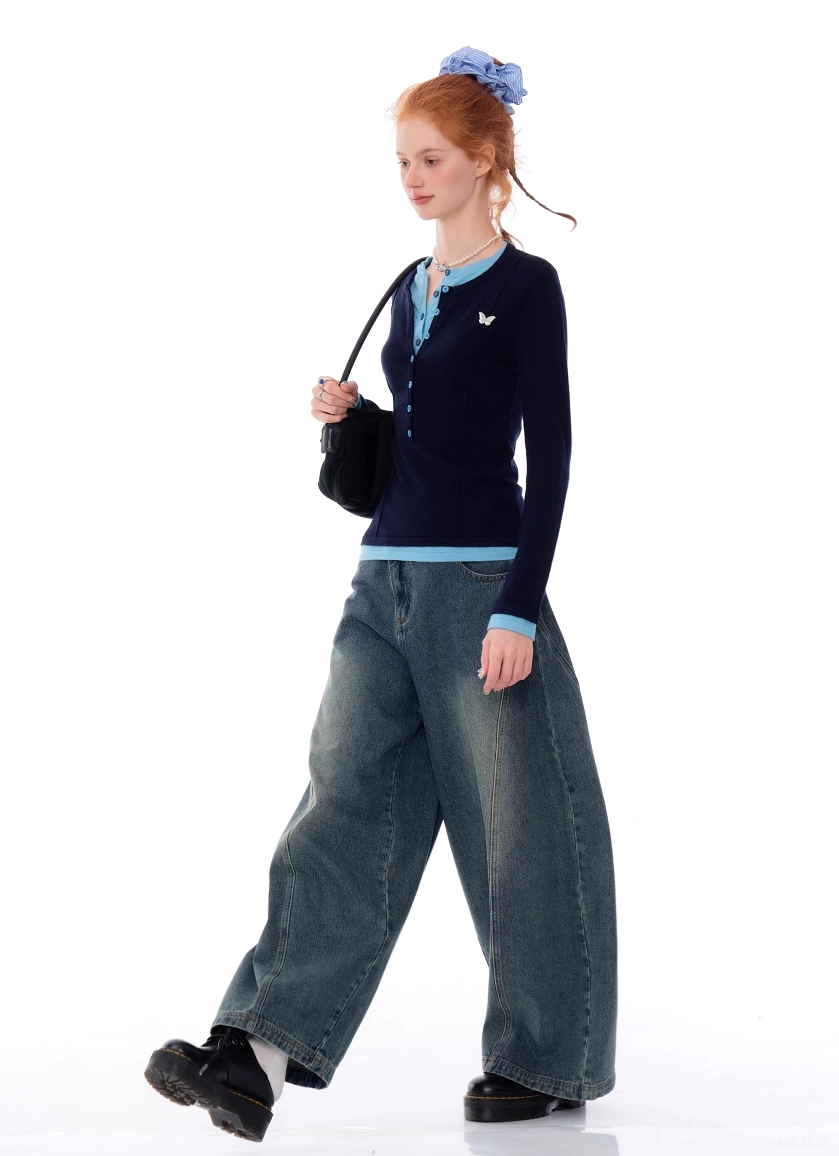 Side walking view of navy blue butterfly Henley knit top with powder blue trim and wide leg denim