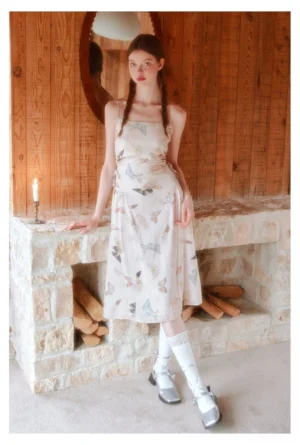 Butterfly print spaghetti strap midi dress styled with white socks and silver Mary Jane shoes in a vintage interior