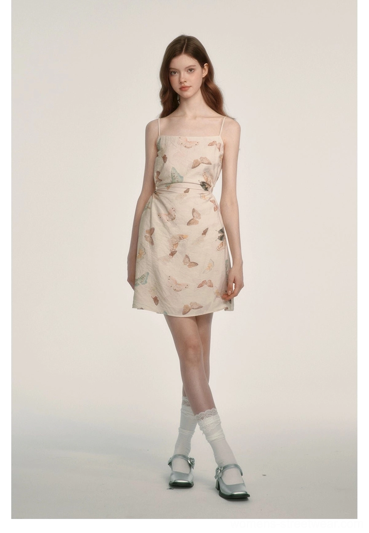 Front full-body view of a butterfly print spaghetti strap mini dress with a fitted waist on a plain studio background