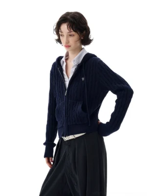 Dark navy cable knit hoodie shown in a three-quarter view with a buttoned midi skirt and belt