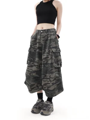 Front view of unisex dark camouflage cargo culottes with oversized thigh pockets, wide cropped legs, black crop top, socks, and outdoor sneakers in a streetwear outfit