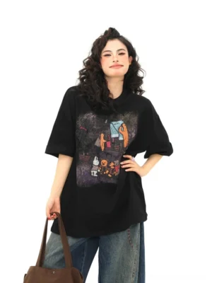 Campfire bear graphic oversized black streetwear T-shirt front view styled with dark wide-leg jeans and brown tote bag