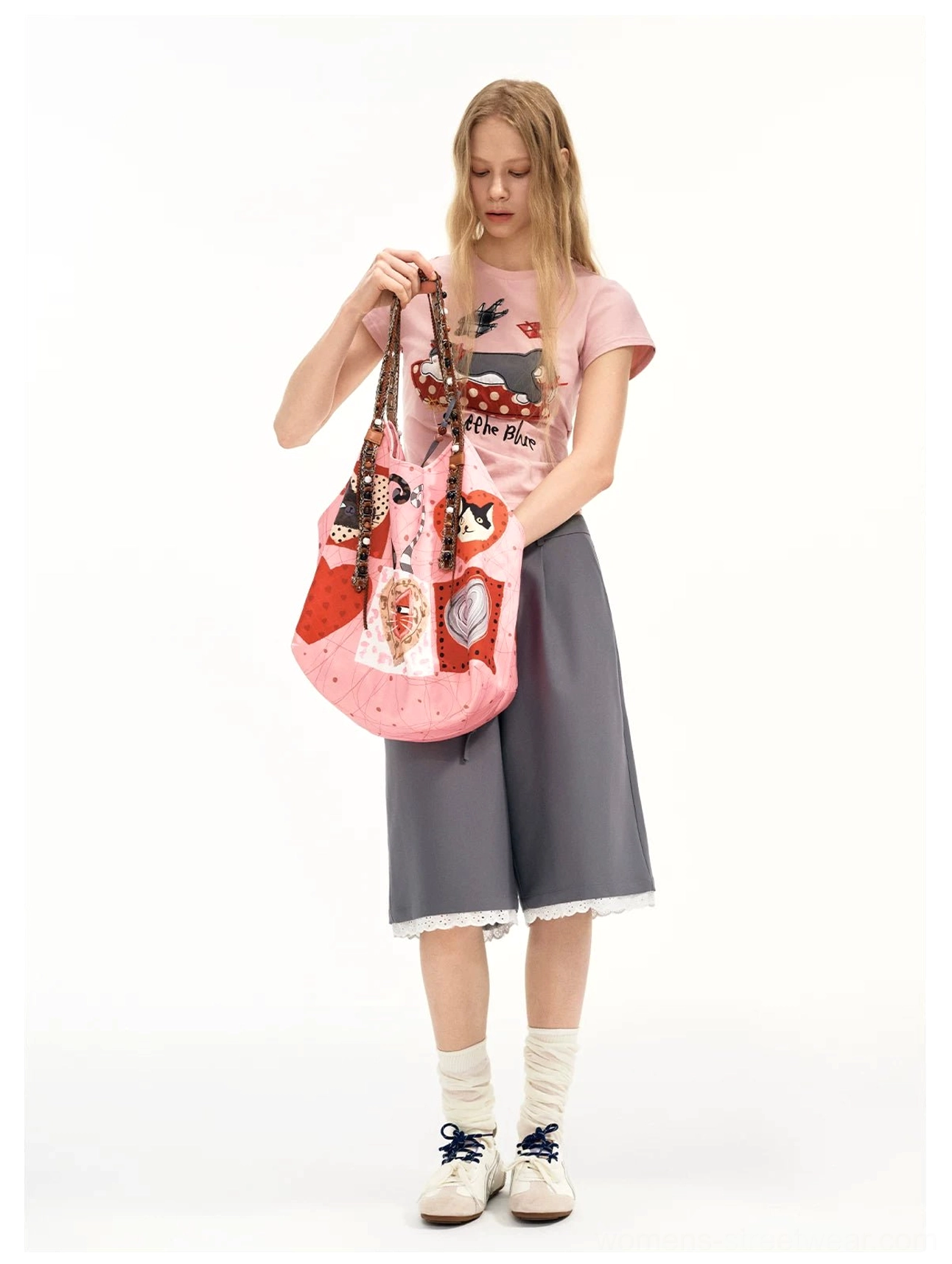 Front view of a candy pink kitty heart patchwork tote worn with a graphic pink tee, cropped gray wide leg shorts, loafers, and socks