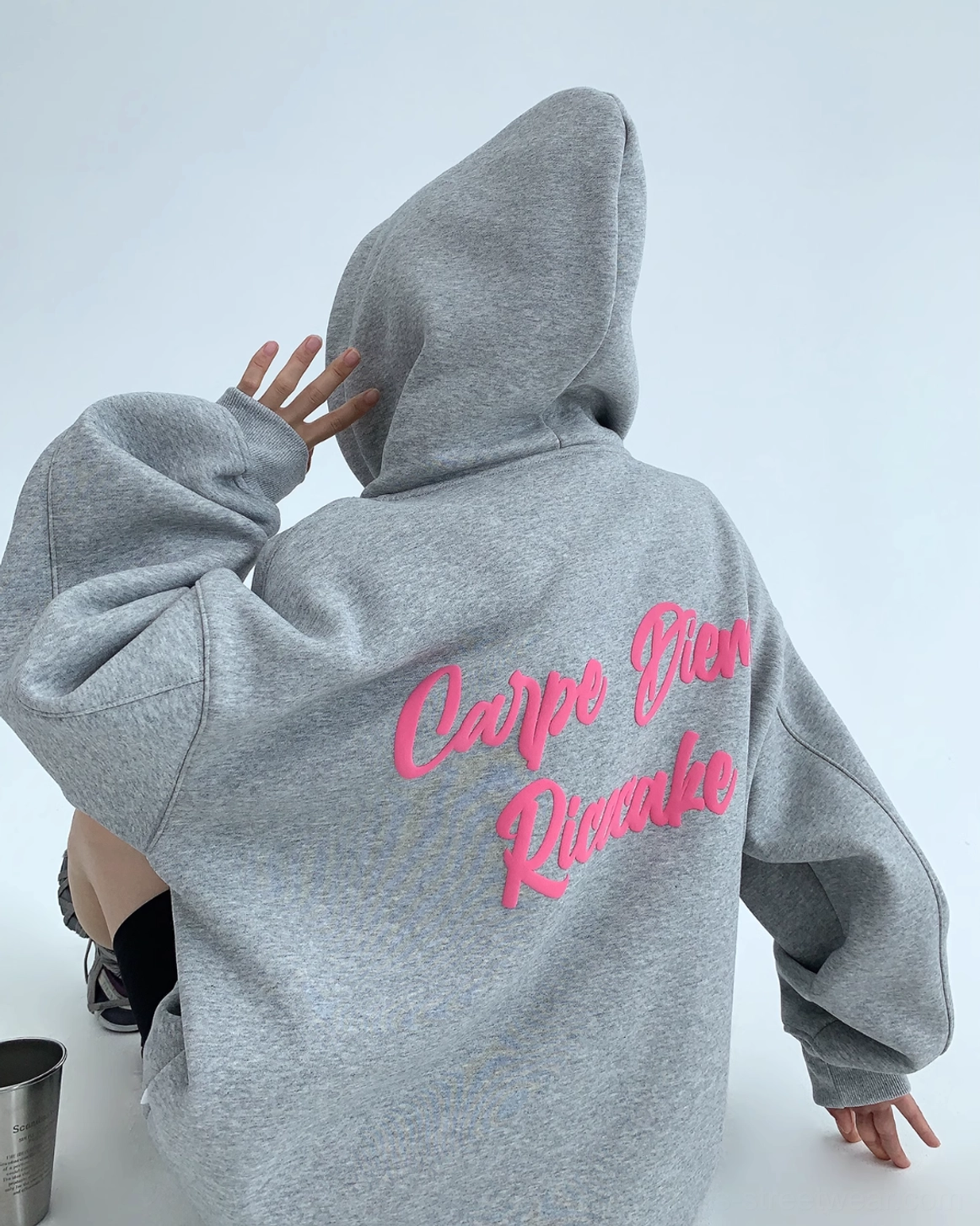 Rear overhead view of gray oversized Carpe Diem hoodie with hot pink script back graphic and roomy hood
