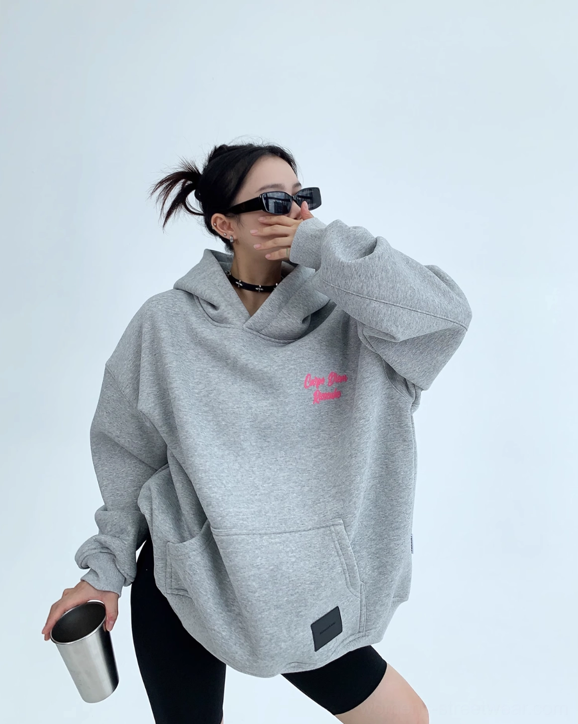 Side front view of gray oversized streetwear hoodie featuring small hot pink Carpe Diem chest script