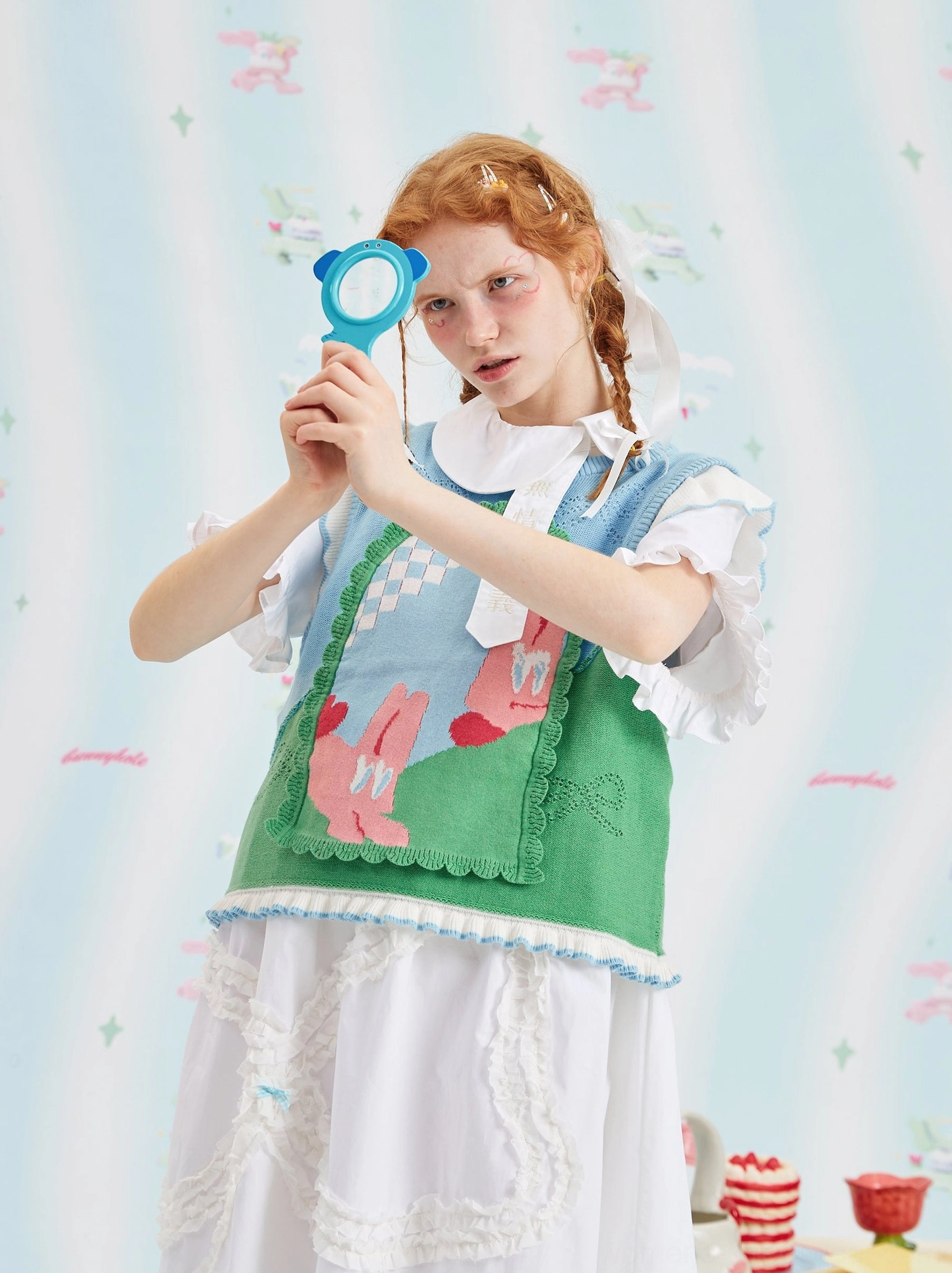 Close-up of mint green cartoon bunny jacquard sweater vest with textured knit pattern and scalloped hem
