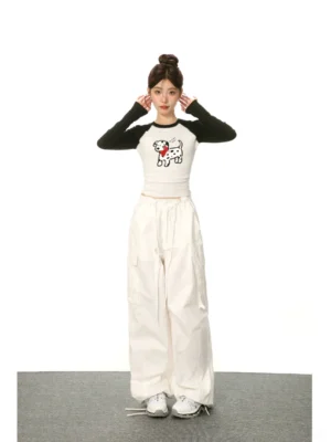 Full front view of a cartoon Dalmatian graphic cropped raglan long sleeve streetwear T-shirt styled with white cargo pants and white sneakers