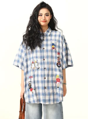 Female model wearing a blue and white oversized plaid cartoon embroidered button-up shirt with wide-leg jeans in a Korean streetwear outfit