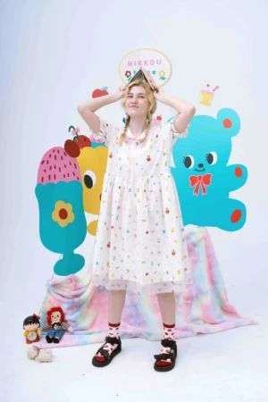 Front view of a white cartoon print sailor collar ruffle babydoll dress with colorful dessert and animal motifs and sheer tulle hem