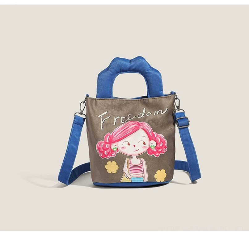 Alternative style cartoon canvas tote front three-quarter view with dark brown body featuring pink curly-hair girl and Freedom text embroidery