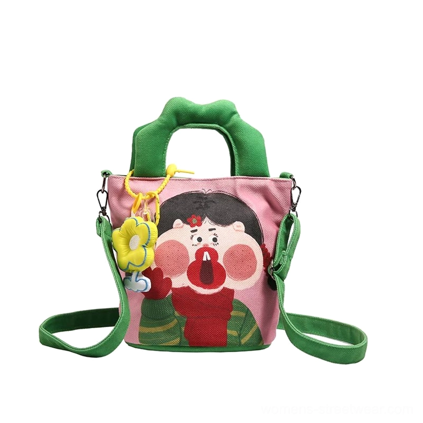 Scale reference image of cartoon canvas tote showing compact size perfect for phone wallet and daily essentials storage