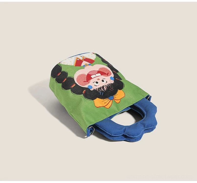 Top-down oblique flat lay of cartoon canvas tote laid sideways showing reverse fabric and blue padded bottom handle detail