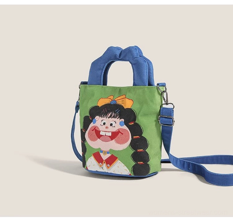 Rear three-quarter perspective of cartoon canvas tote bag showing metal buckle hardware and adjustable shoulder strap attachment system