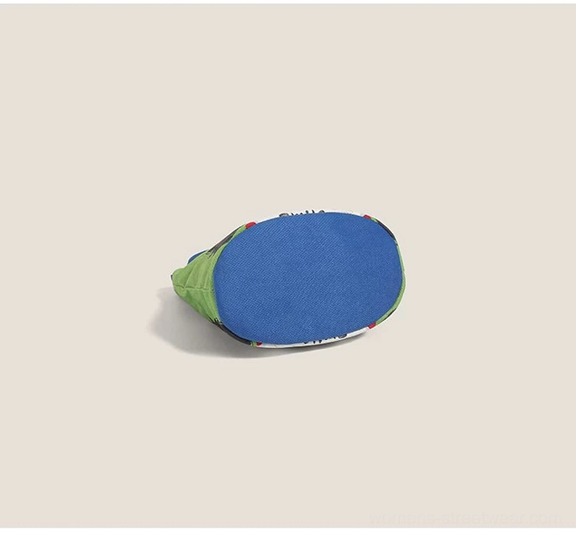 Side flat lay perspective of cartoon canvas tote showing blue bottom panel and green side fabric without print pattern