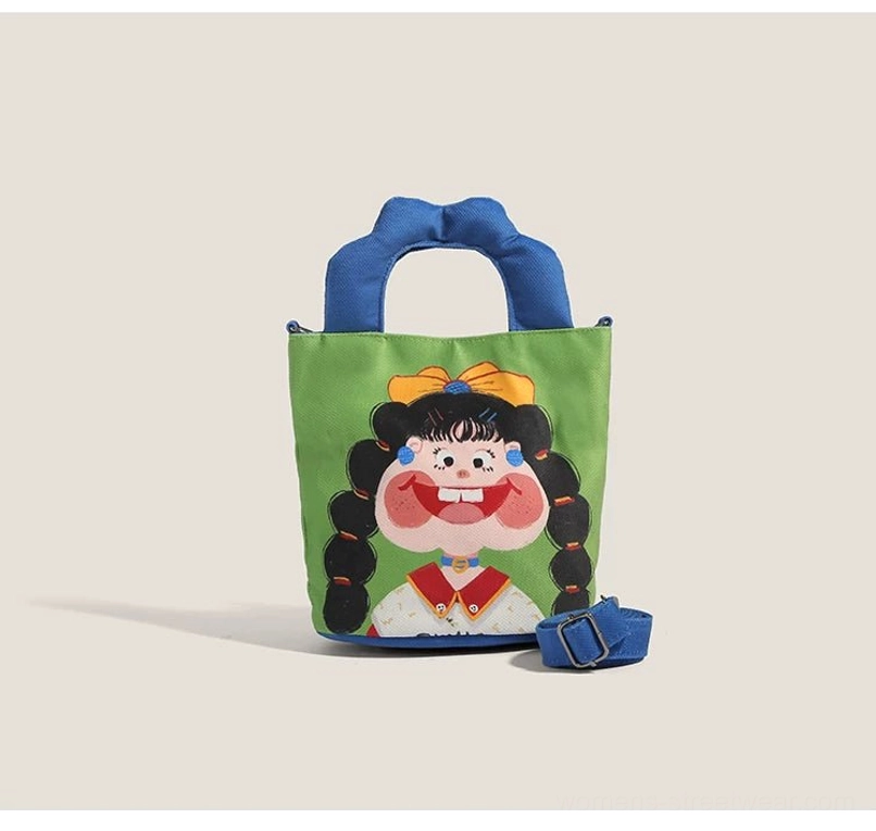 Side view of cartoon canvas tote bag with detachable blue shoulder strap displayed beside showing full front character illustration