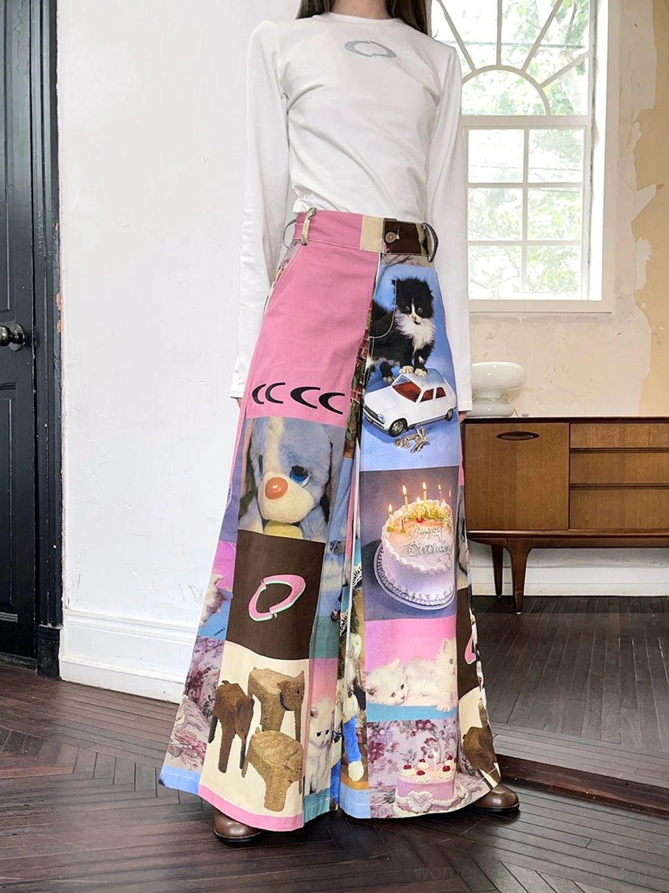 Back full-body view of high-waist cat and birthday cake print wide-leg pants with colorful patchwork graphics