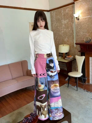 Front full-body view of pink cat and birthday cake print high-waist wide-leg streetwear pants in a vintage living room