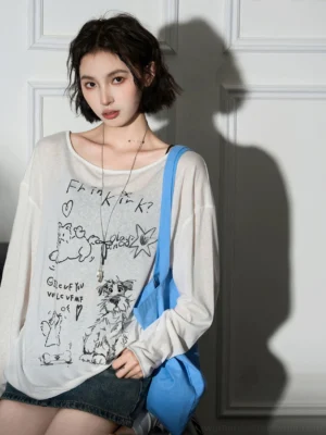 Relaxed fit cat print off-shoulder sheer blouse with black cartoon graphics styled with layered necklaces and denim mini skirt