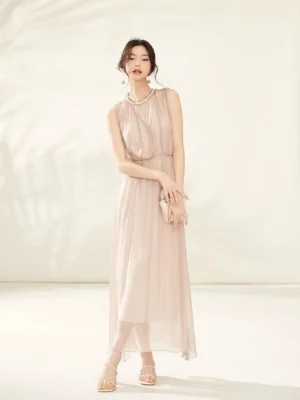 Front view of champagne pink pearl embellished silk midi dress with gathered bodice elastic waist sheer flowing skirt and clutch bag