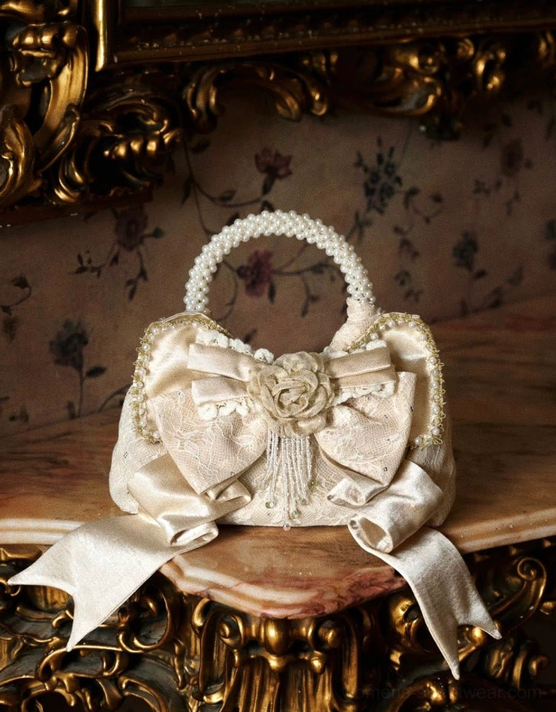 Champagne pearl handle rosette bow mini handbag displayed front view on a vintage carved wooden table