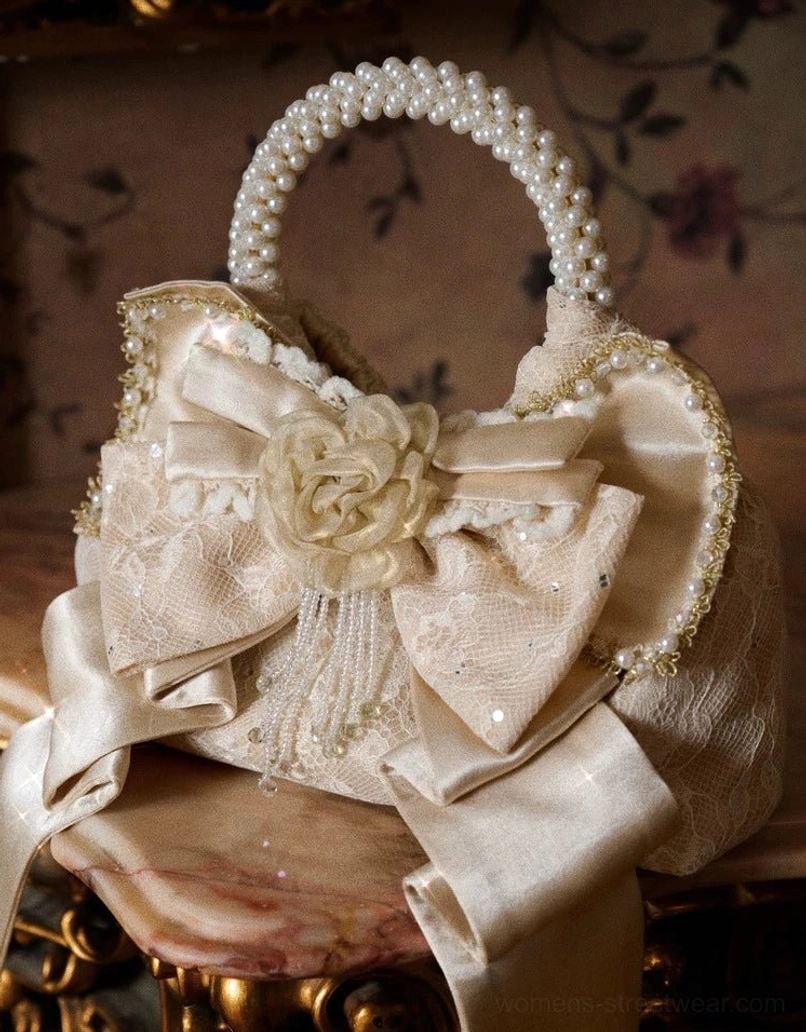 Front close-up of champagne pearl handle rosette bow mini handbag with fabric rose and crystal tassel