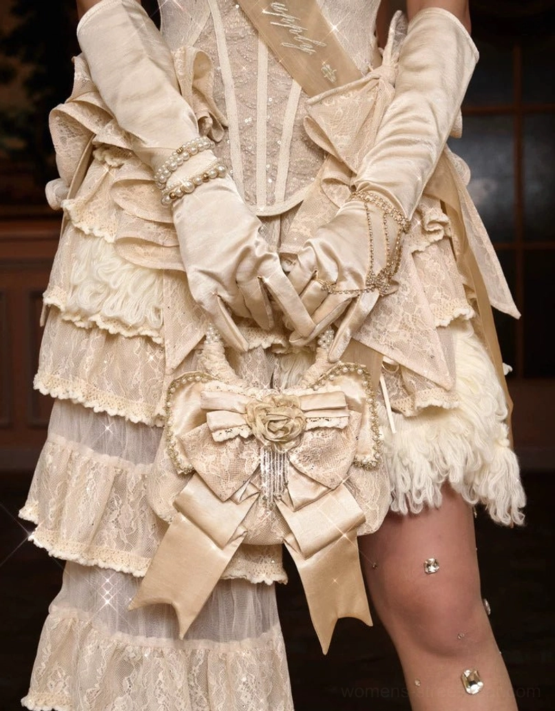 Champagne rosette bow mini handbag worn at the hip with ruffled lace dress and satin gloves