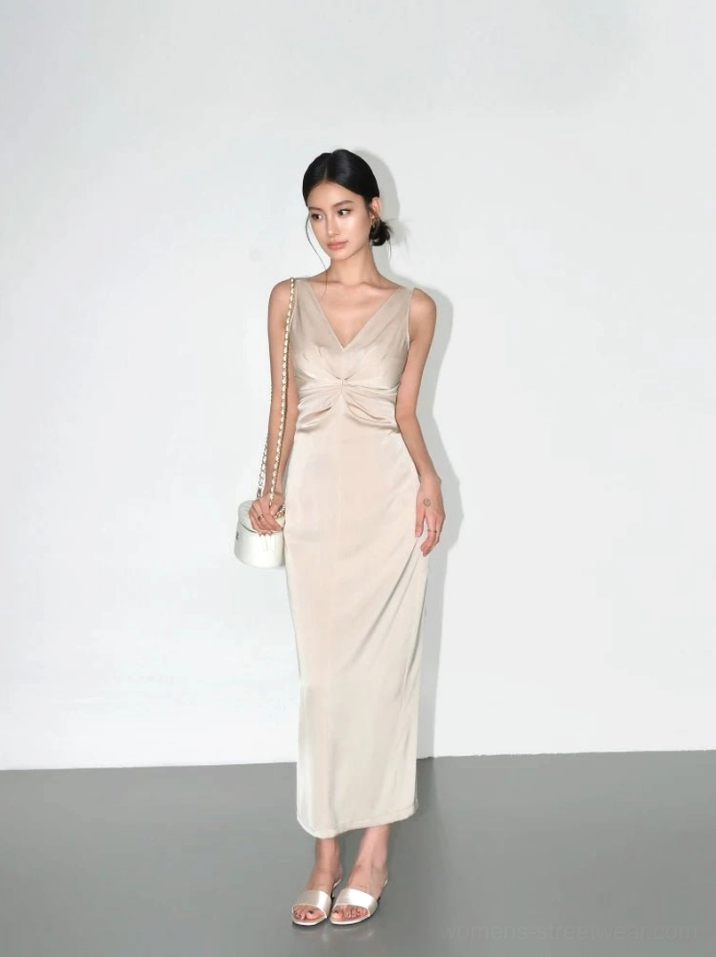 Champagne satin twist-front maxi slip dress shown from a side-front angle with slim floor-length cut, high heels and mini shoulder bag