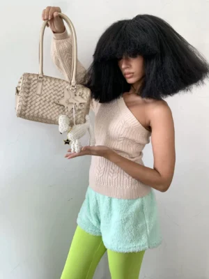 Champagne beige woven Boston handbag held by model with star charm, double handles, and braided leather texture