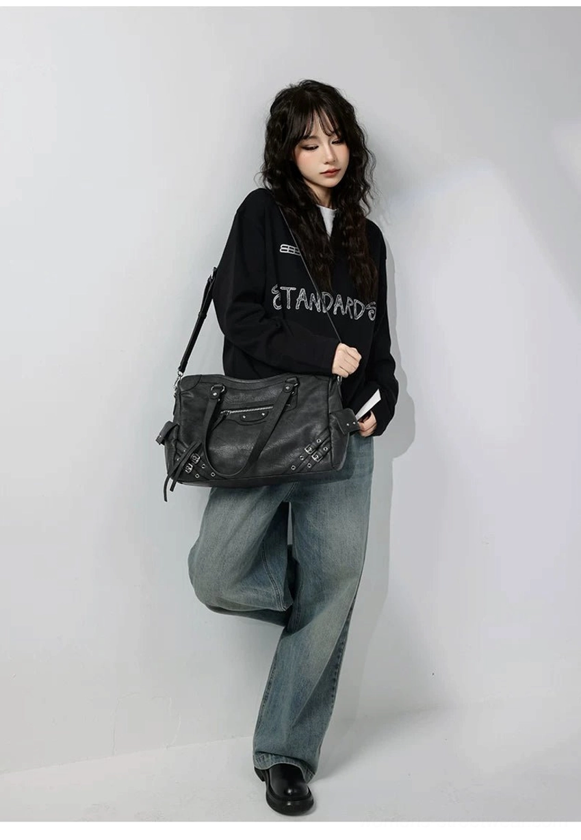 Charcoal buckle rider tote bag full body side styling with vintage motorcycle details and casual urban fashion