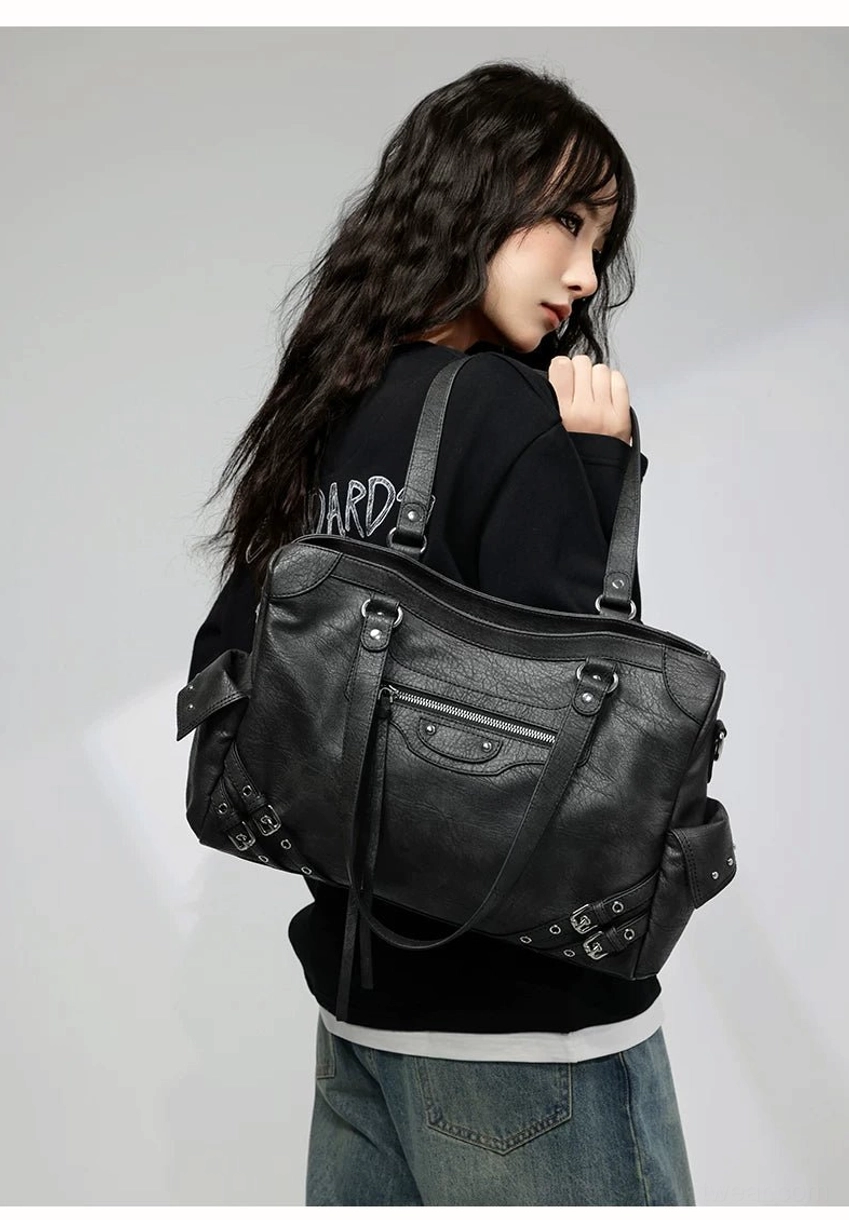 Charcoal buckle rider tote bag worn over the shoulder showing vintage wrinkled faux leather and adjustable strap