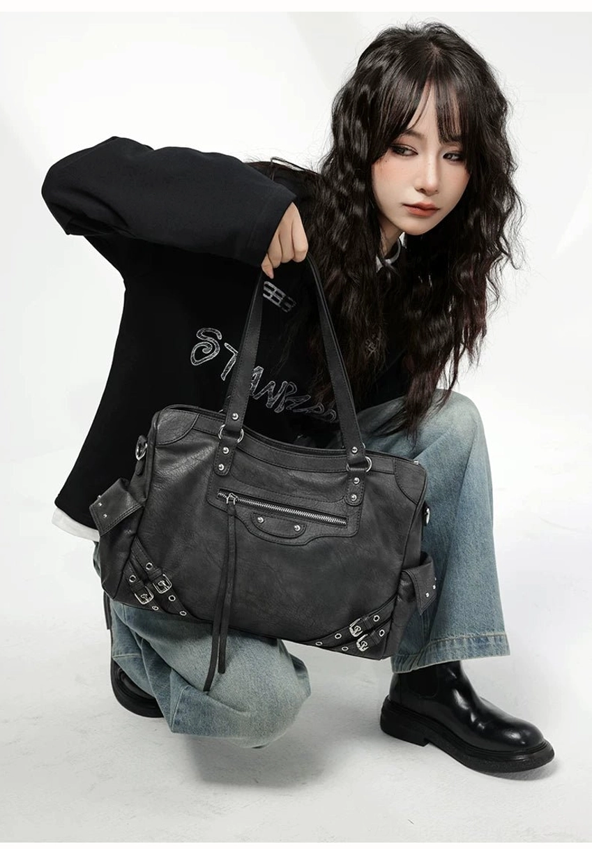 Charcoal buckle rider tote bag close front view with tassel zipper pulls decorative metal trims and structured body