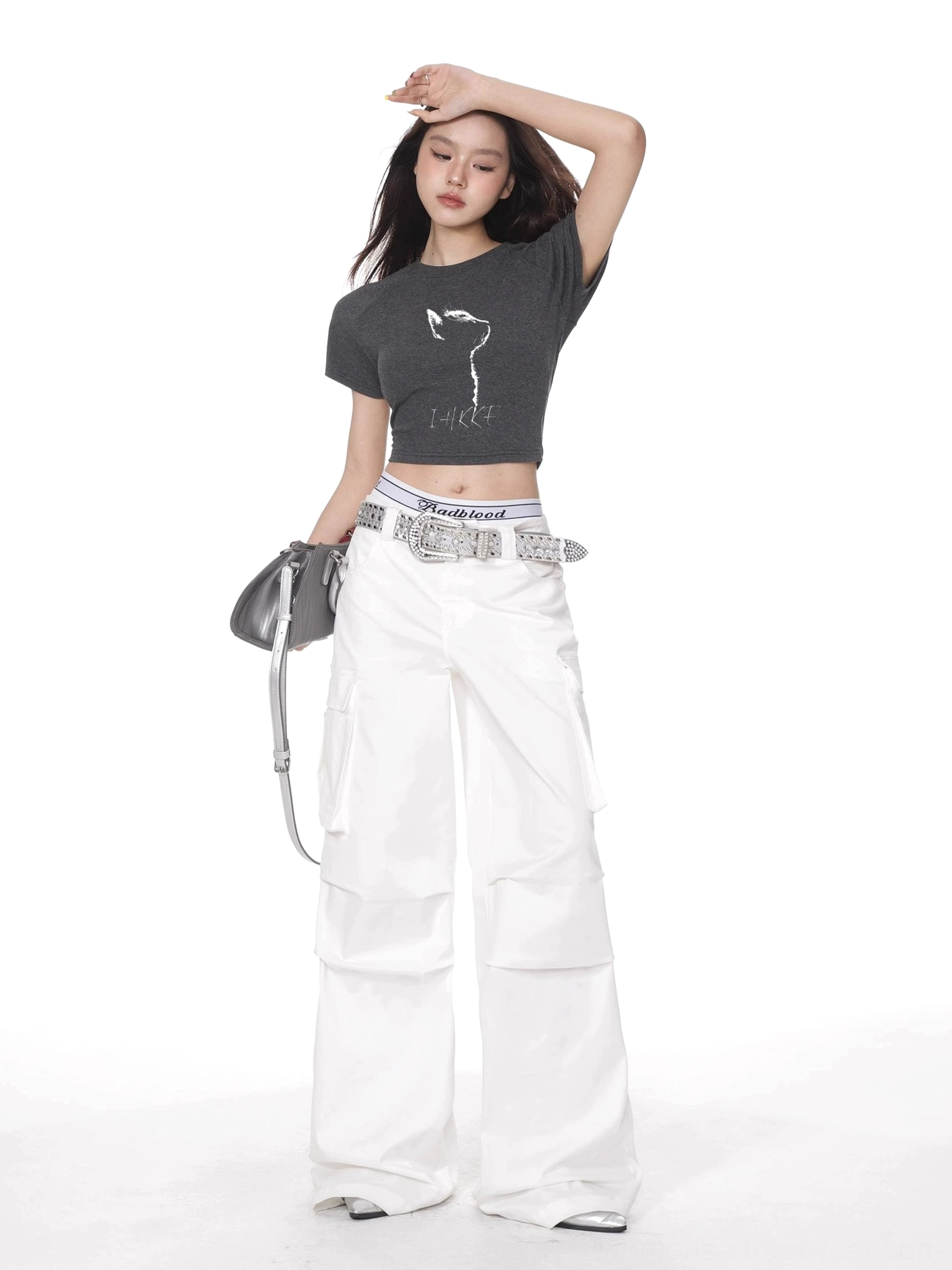 Dark charcoal cat graphic cropped fitted t-shirt styled with white cargo pants and gray crossbody bag
